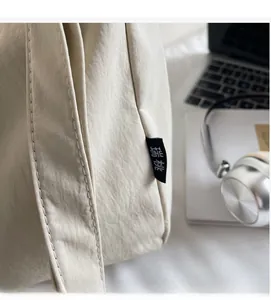 Close-up of minimalist beige canvas bag featuring brand tag and precision stitching details