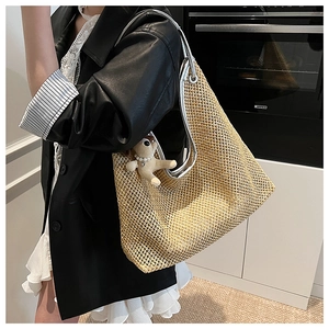 Detailed shot of large straw tote bag with silver handles and a cute bear charm accessory