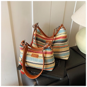 Détail du sac bandoulière tissé arc-en-ciel avec bandoulière en similicuir brun et breloque fraise