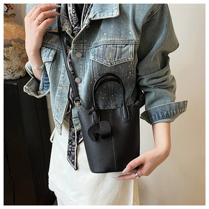 Detail of black lychee grain bucket bag featuring a cute elephant charm and long strap