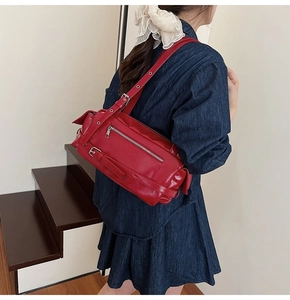 Detail of dark red PU leather pillow bag with silver metal buckles and retro straps