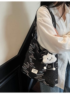 Black quilted drawstring tote bag with colorful embroidery and white plush cloud charm