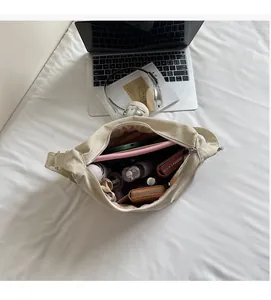 Top view of spacious interior in cream canvas dumpling bag with tablet and daily essentials