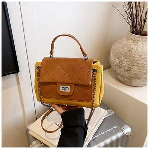 Detail of rhombic quilted crossbody bag with metal chain strap and twist-lock closure
