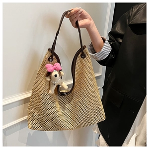 Detail of woven straw tote bag with brown leather straps and a cute puppy plush charm