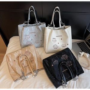 Détail de quatre cabas colorés avec imprimés chat et chaîne métal dans un cadre cosy