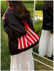Détail du sac cabas en maille rayée rouge et blanc montrant la texture et la bandoulière