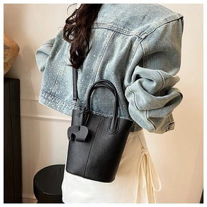 Close-up of black litchi leather bucket bag featuring a decorative elephant charm pendant