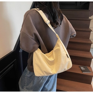 Detail of adjustable wide shoulder strap and metal buckle on beige canvas hobo bag