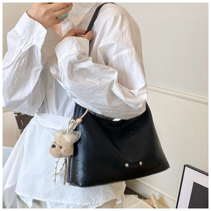 Détail du sac bandoulière minimaliste noir avec clous argentés et breloque ours