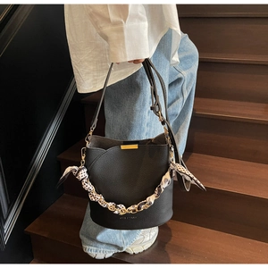 Détail du sac seau noir grainé avec chaîne en foulard de soie et décor doré