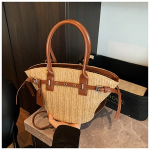 Close-up of woven straw tote bag with brown leather handles and metal eyelet accents