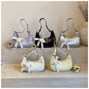 Macro detail of half-moon shoulder bags with pearl bow charms in five vibrant colors