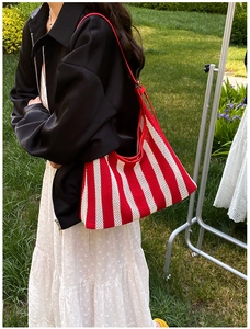 Vue latérale du sac fourre-tout en tricot rayé rouge et blanc avec bandoulière en cuir