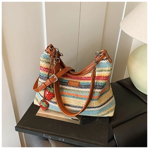 Détail d'un sac cabas en paille arc-en-ciel avec breloques fraises et étiquette en cuir