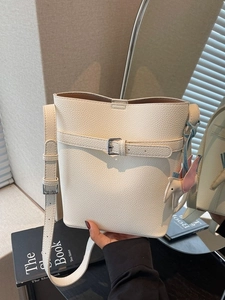 Elegant off-white lychee textured bucket bag with decorative buckle and elephant charm