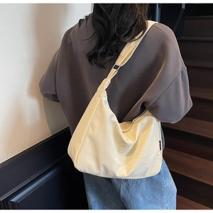 Detailed back view of a cream minimalist large capacity canvas dumpling bag on a model