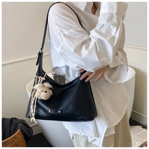 Détail du sac croissant noir plissé en cuir avec un joli pendentif ours en peluche