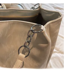 Nahaufnahme der silbernen Metallkette an einer cremefarbenen Shopper-Tasche mit Struktur