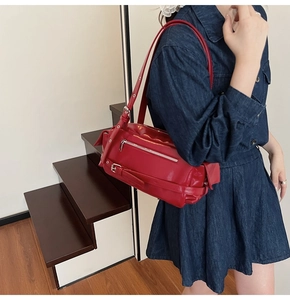 Detail of red glossy leather shoulder bag with silver zipper and adjustable strap