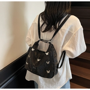 Detail of silver butterfly charms on a black pleated high-capacity versatile backpack