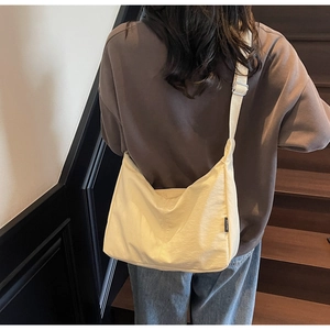 Detail of a beige canvas dumpling bag with RUI TAO side tag on a wooden staircase