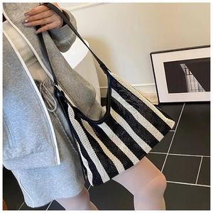 Détail du sac hobo en tricot à rayures noires et blanches avec bandoulière en cuir