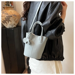 Detail view of light blue bucket bag with lychee texture and elephant charm on model
