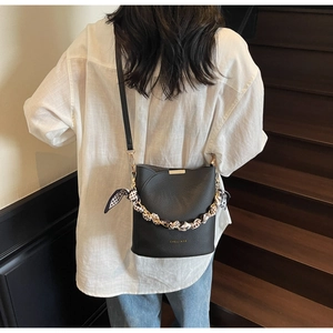 Détail du sac seau noir en cuir foulonné avec foulard en soie et finitions dorées