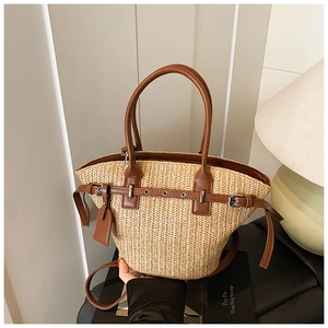 Detail of woven straw bucket bag with brown faux leather handles and metal hardware