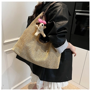 Detail of woven straw tote bag with brown leather straps and cute plush puppy charm