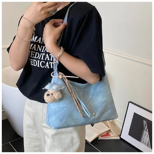 Détail du sac hobo bleu clair en daim doux avec un adorable pendentif en forme d'ourson