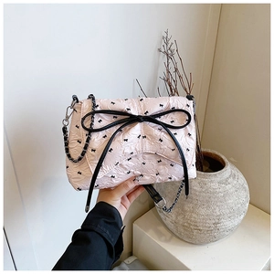 Dettaglio della borsa a cuscino rosa trapuntata con fiocchi neri e tracolla a catena