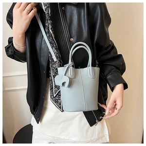 Detail of light blue bucket bag with lychee texture and cute elephant charm