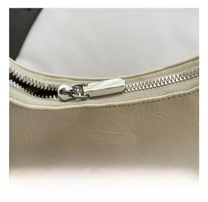 Macro detail of high-quality silver zipper and textured ivory leather on crossbody bag