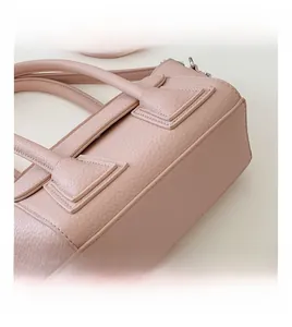 Macro shot of pink lychee grain leather handbag featuring neat stitching and metal hardware