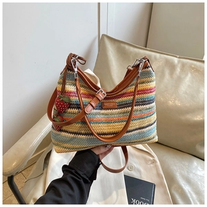Détail du sac tissé arc-en-ciel avec bandoulière en cuir et breloques fraises