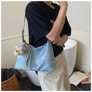 Détail du sac rétro bleu ciel avec pendentif ours en peluche et plaque de marque en métal