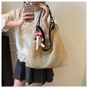 Detail of straw tote bag featuring black leather straps and a cute puppy plush charm