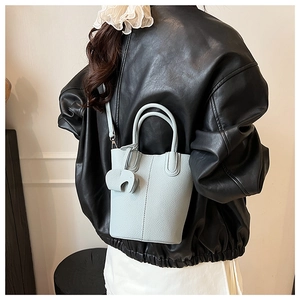 Detail of light blue bucket bag with pebble texture and cute elephant charm on a model