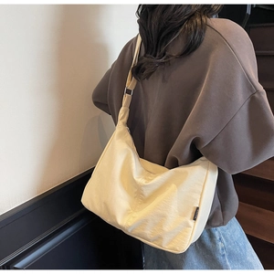 Detailed close-up of cream canvas dumpling bag showing premium fabric texture and shoulder strap