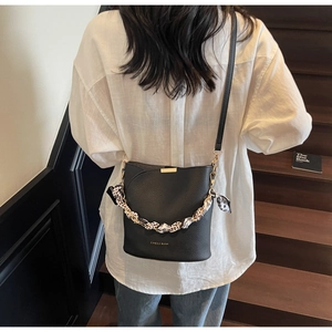 Détail du sac seau en cuir noir grainé avec foulard léopard et logo doré chic