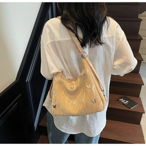Close-up of apricot hobo bag featuring glossy pleated texture and silver butterfly details