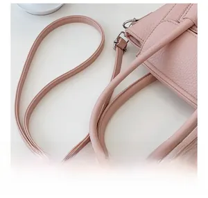 Detail view of pink pebbled leather handbag with adjustable strap and silver metal hardware