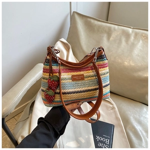 Détail du sac tissé arc-en-ciel avec pendentifs fraises rouges et bandoulière en cuir brun