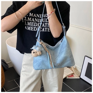 Détail du sac hobo bleu clair vintage avec pendentif ours et pompon tressé décoratif