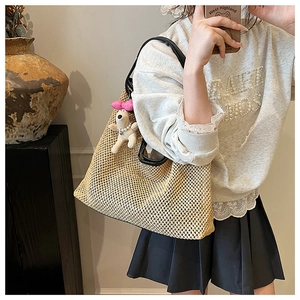 Detail of woven straw tote bag with black leather straps and a cute dog plush charm