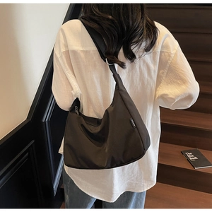 Close-up of black nylon dumpling bag with adjustable shoulder strap and side label detail
