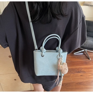 Detail of light blue pleated mini tote bag with knotted handle and plush bear charm