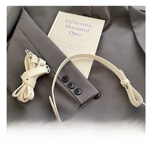 Detail showing high-quality leather handle and adjustable shoulder strap on a beige handbag